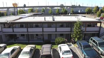 A parking lot with several cars parked in front of a building with a flat roof and multiple windows.