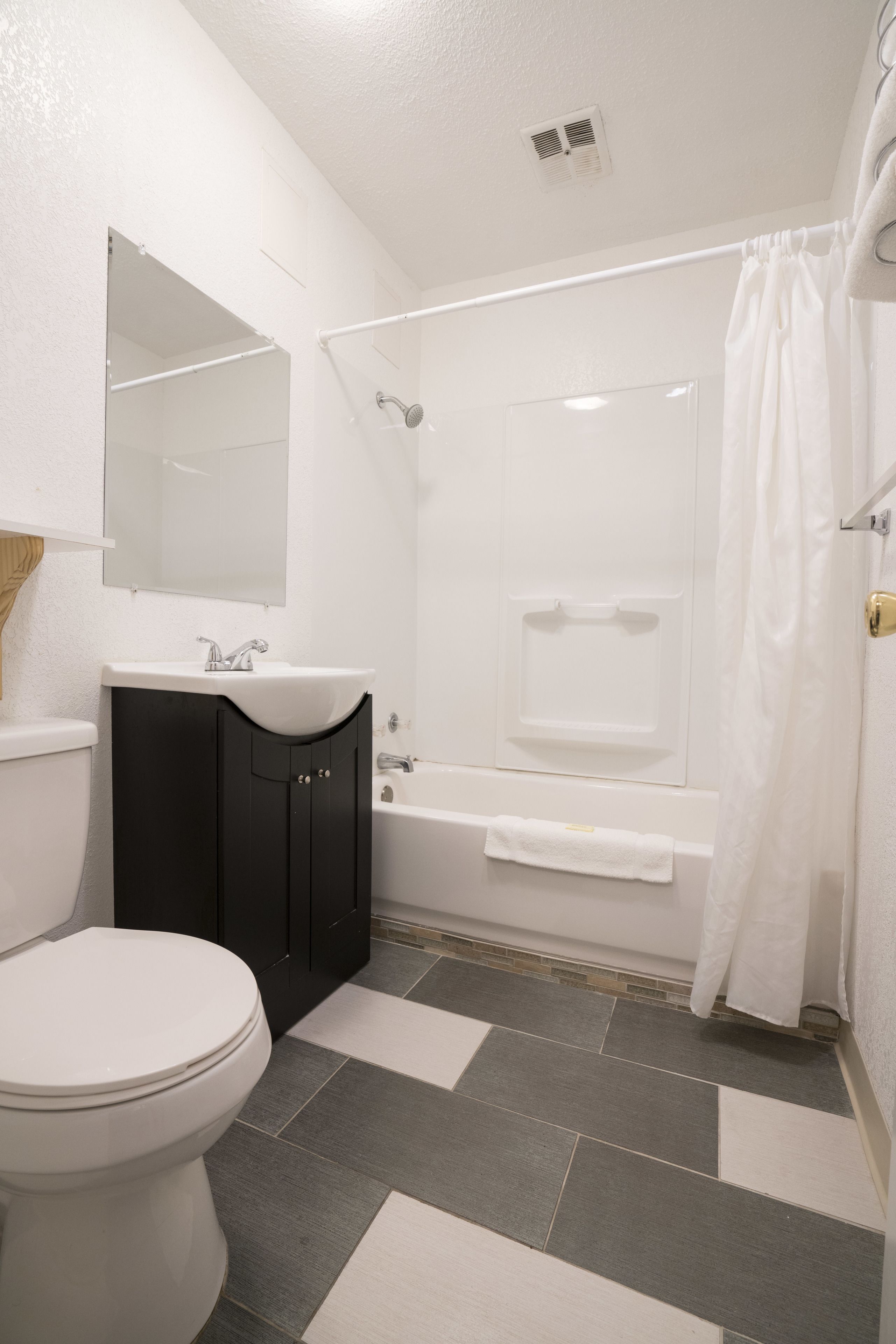 A bathroom with a toilet, sink, mirror, bathtub, and shower curtain.