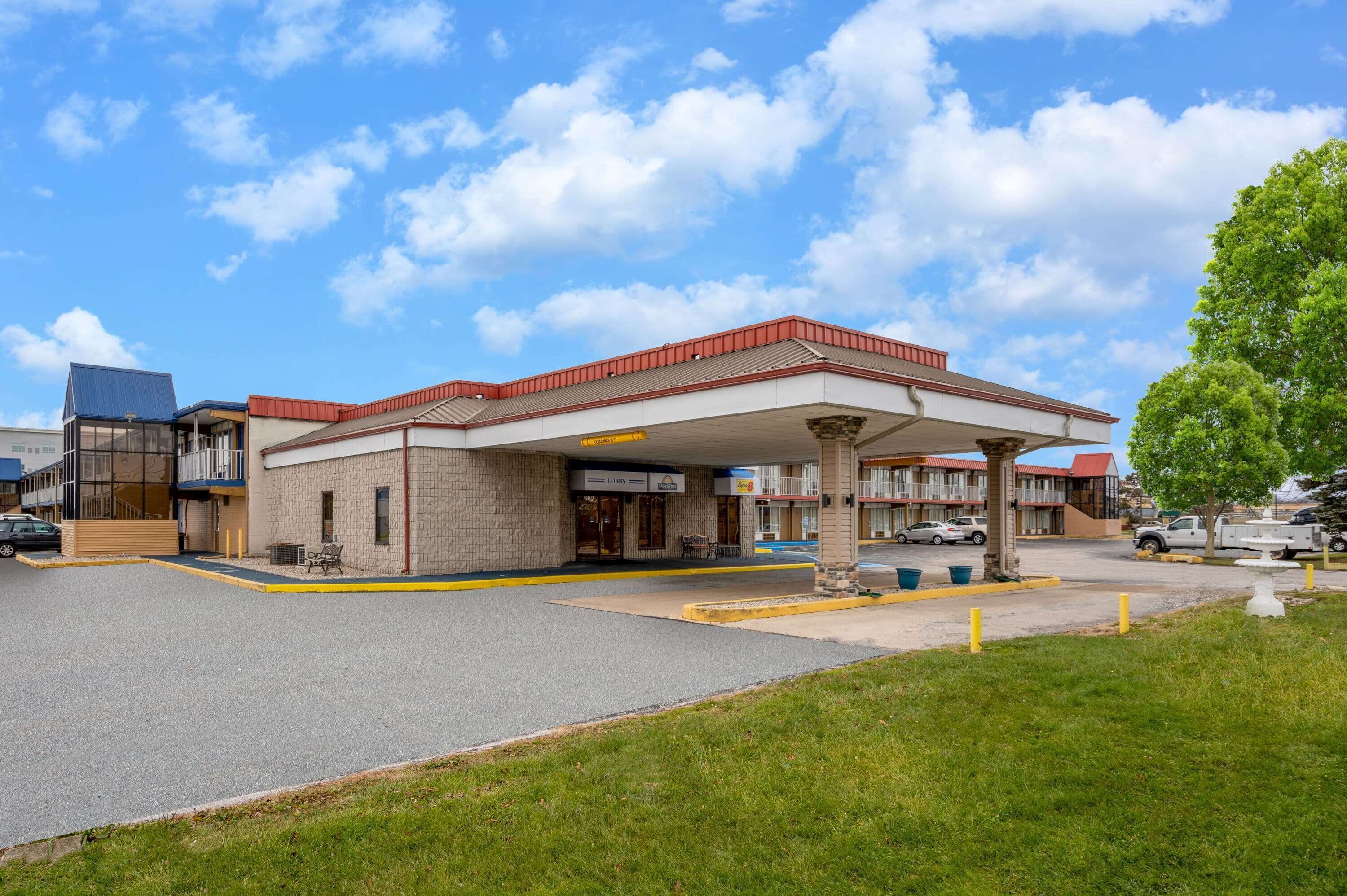 A motel with a gas station, a parking lot, and a grassy area.