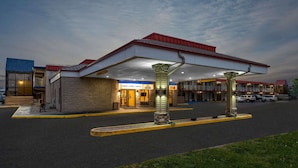 A motel with a covered parking area, multiple stories, and a visible entrance. - Super 8 by Wyndham Perrysburg/Toledo (Perrysburg)