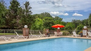 A swimming pool with white lounge chairs and an orange umbrella. - Quality Inn Mount Airy Mayberry (Mount Airy)