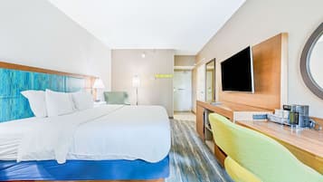 Ein Hotelzimmer mit Bett, Schreibtisch, Stuhl, Fernseher und einem Badezimmer im Hintergrund.