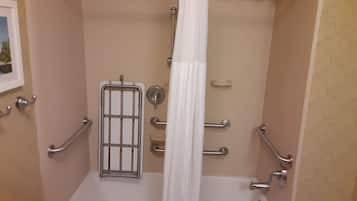 A bathroom with a bathtub, grab bars, a shower curtain, and a towel rack.