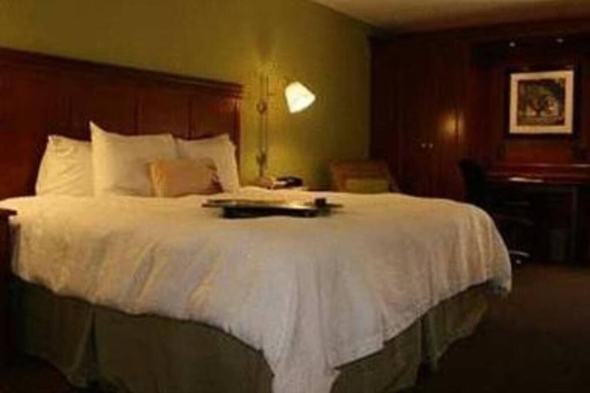 A hotel room with a large bed, a desk, and a chair.