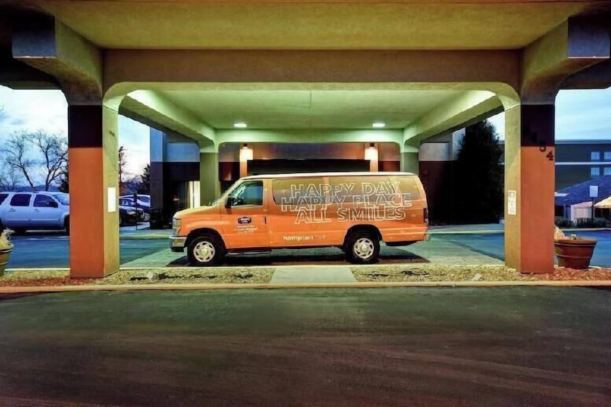A van parked under a covered area with the text 'HAPPY DAY HAPPY PLACE ALL SMILES' on its side.