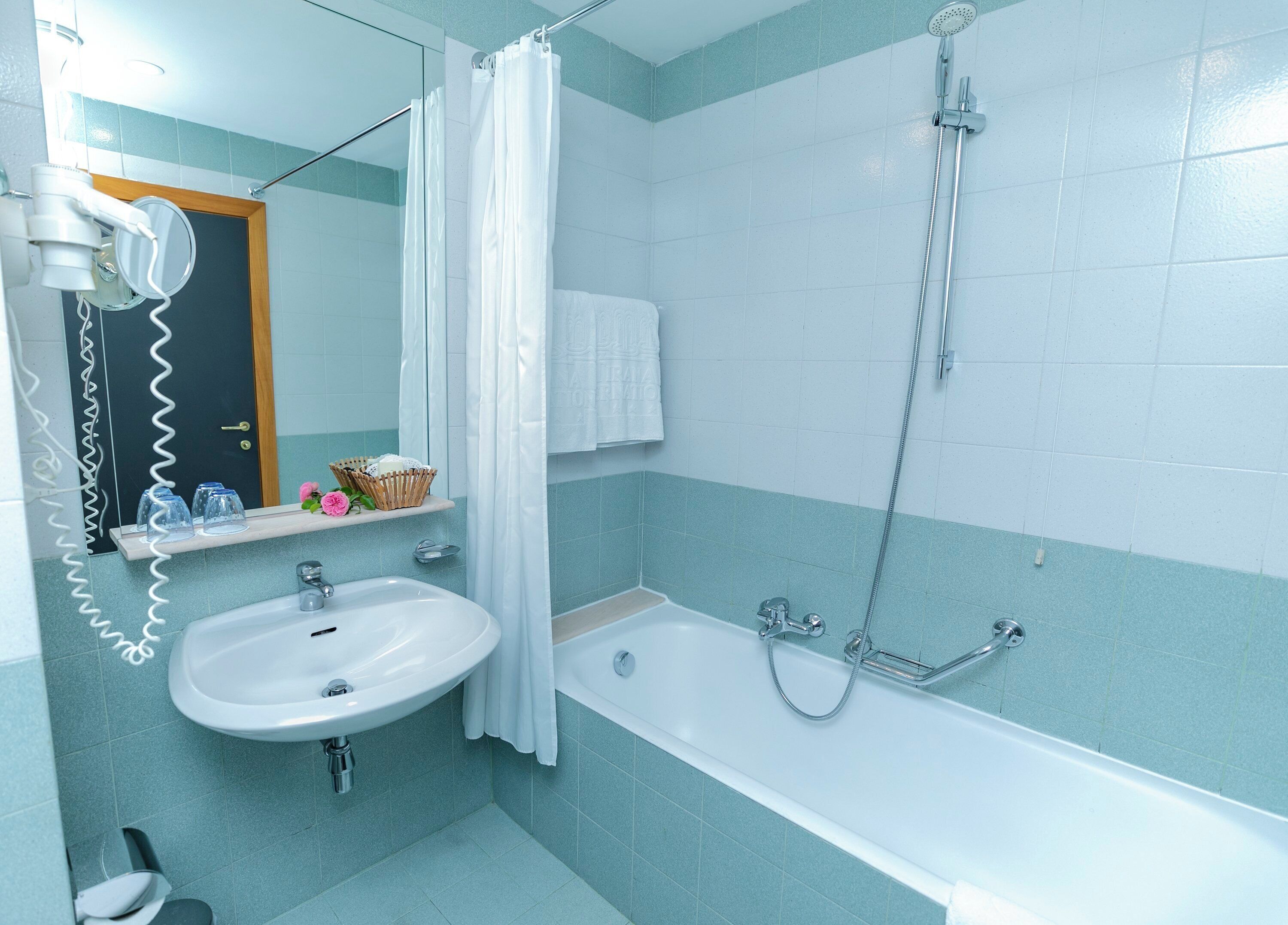 A bathroom with a sink, bathtub, shower, and a mirror.