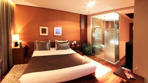 Une chambre d’hôtel avec un grand lit, une télévision, un bureau et une porte coulissante donnant accès à la salle de bain.