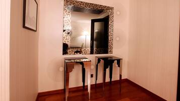 Una stanza con pavimento in legno, una scrivania con specchio e un pannello decorativo a parete.