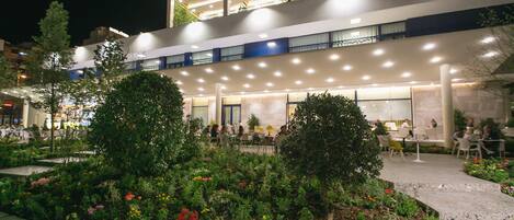 Un hotel moderno con terraza en la azotea, zona de estar al aire libre y un jardín bien cuidado.