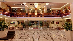 Un hall d’hôtel spacieux, doté d’un sol en marbre, de plusieurs espaces aménagés pour s’asseoir et d’une entrée en verre.