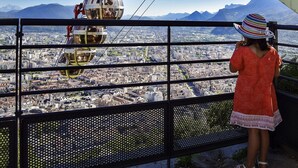 Blick auf eine Stadt von erhöhter Position, vermutlich aus einer Seilbahn oder Aussichtsplattform, über einem dicht bebauten Stadtgebiet mit Gebäuden und Straßen.
