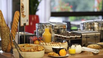 A breakfast buffet with various pastries, bread, and beverages.