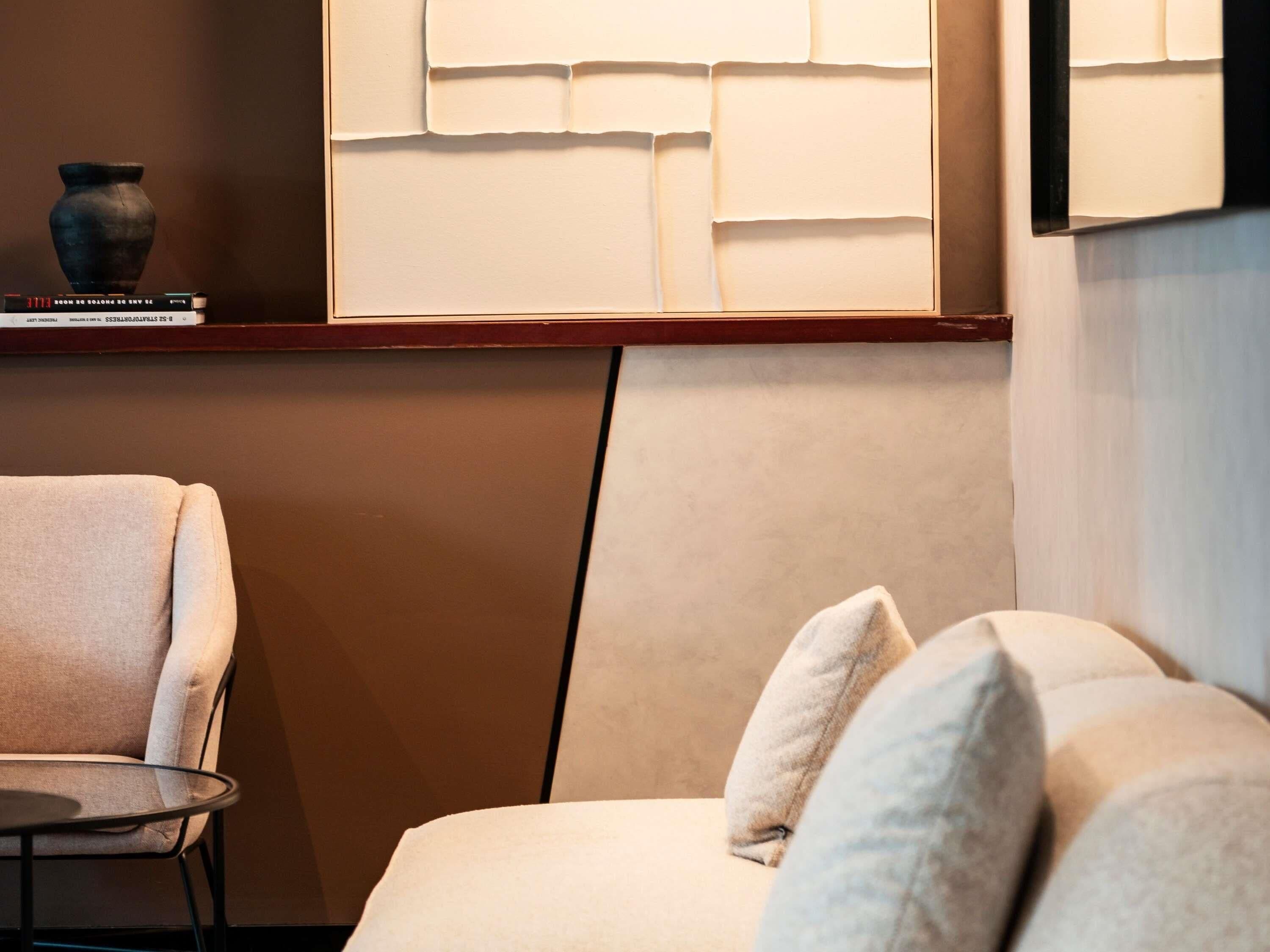 Un intérieur moderne avec un canapé, une petite table ronde et un vase décoratif posé sur une étagère.