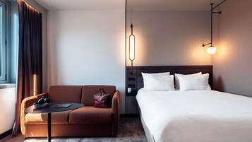 Une chambre d’hôtel moderne comprenant un lit, un canapé, une petite table et une table de chevet.