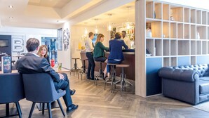 Eine moderne Bar mit einer Theke, Hockstühlen und einer Sitzecke mit einer Couch.
