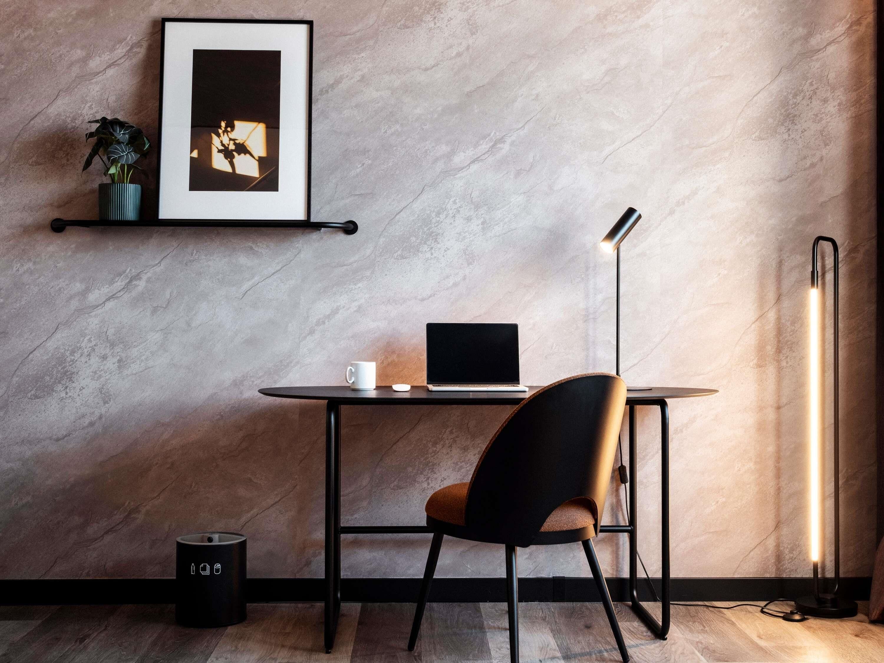 Un espacio de trabajo moderno con escritorio, silla, ordenador portátil y lámpara de pie.