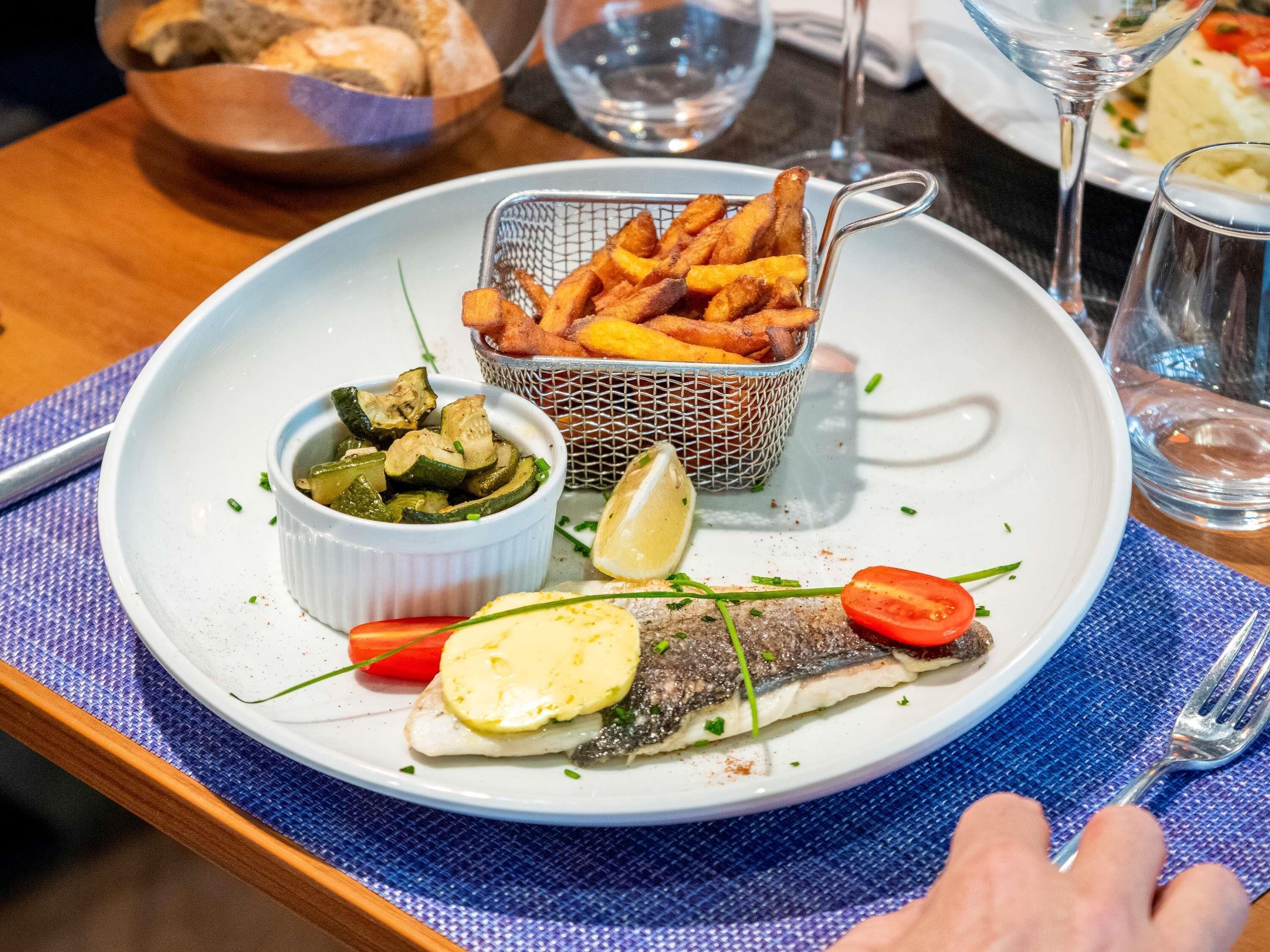 Un plato de pescado, papas fritas y verduras.