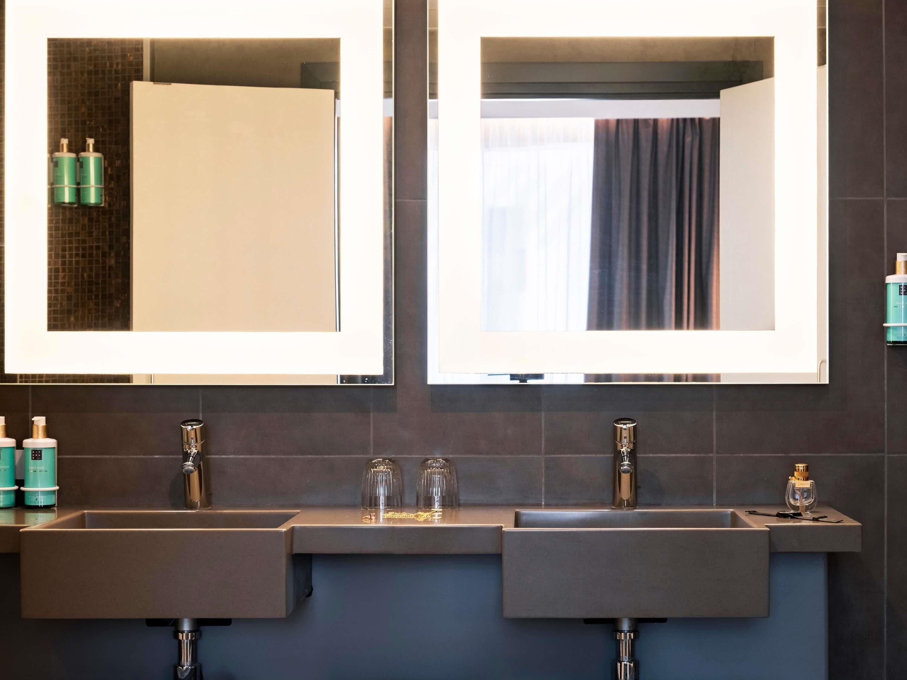 Ein modernes Badezimmer mit zwei Waschbecken, einem Spiegel und einem Fenster.