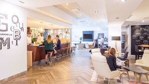 Eine moderne Bar mit Theke, Sitzgelegenheiten und einem großen Bildschirm.