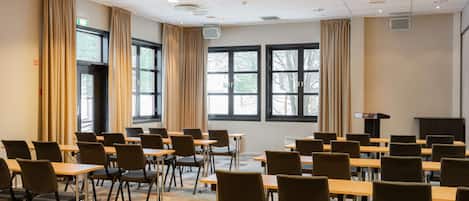 A conference room with multiple tables and chairs, large windows, and a podium.
