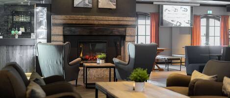 Een moderne lounge met een open haard, comfortabele zitplaatsen en een bar.