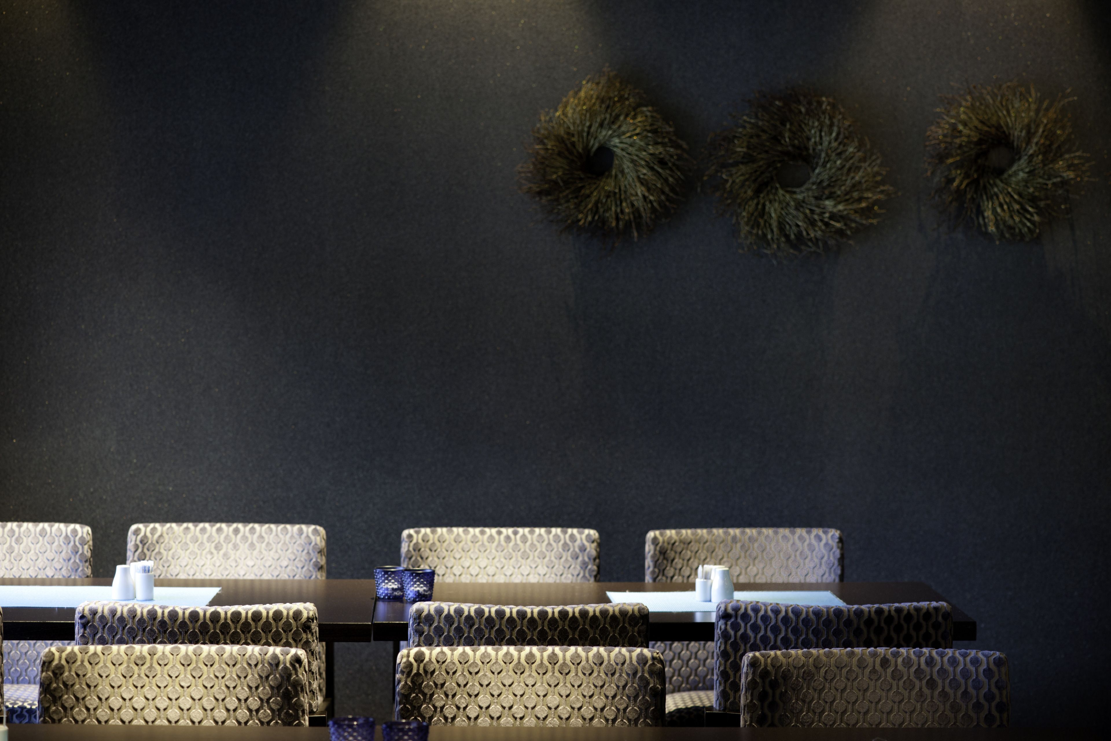 Un salón de conferencias con pared oscura, sillas estampadas y una mesa con mantel blanco.