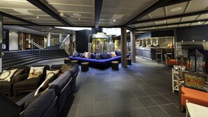 En modern entréhall med en blå soffa, en öppen spis och en bardisk.