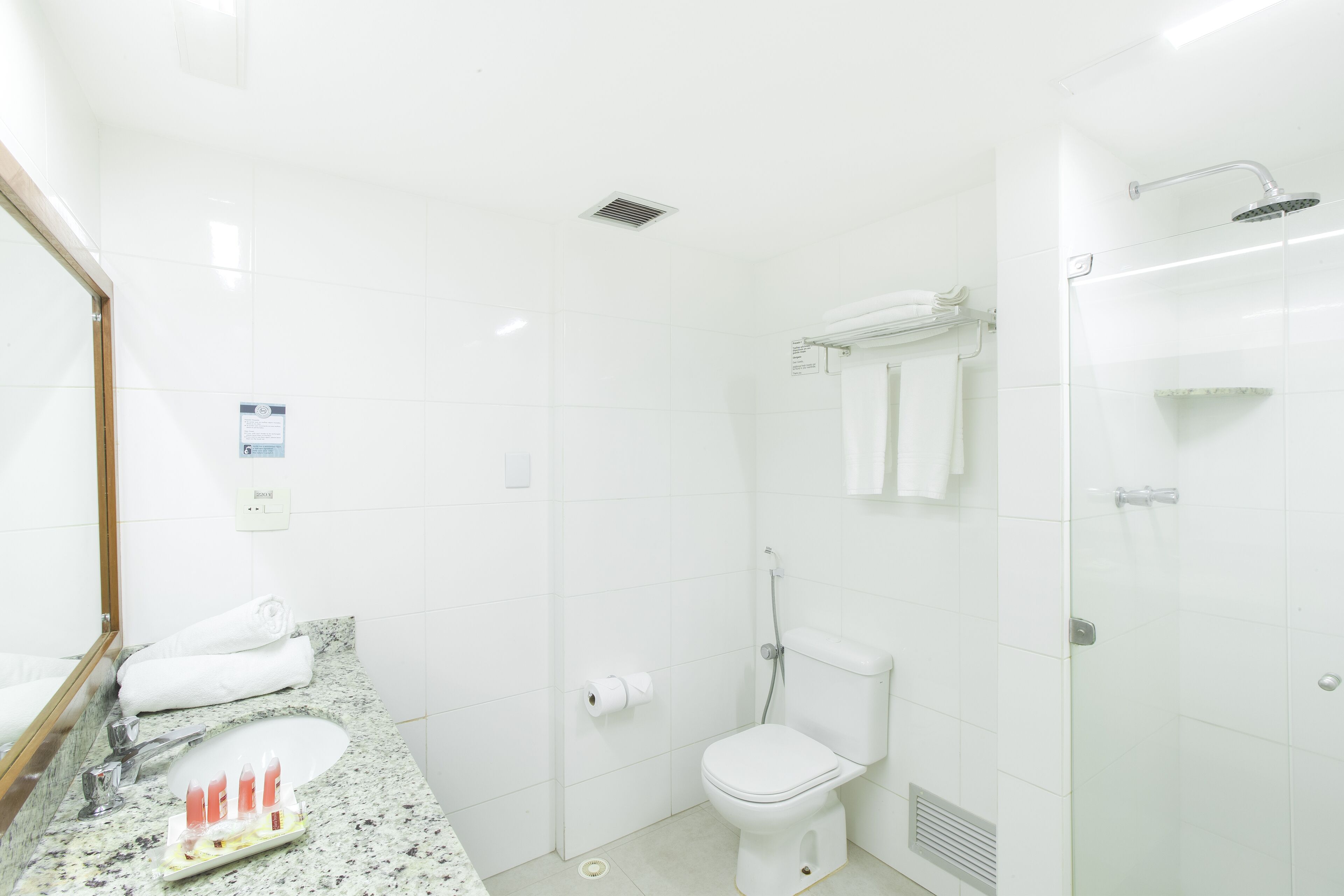 Un baño moderno con lavamanos, inodoro y ducha con cerramiento de vidrio.