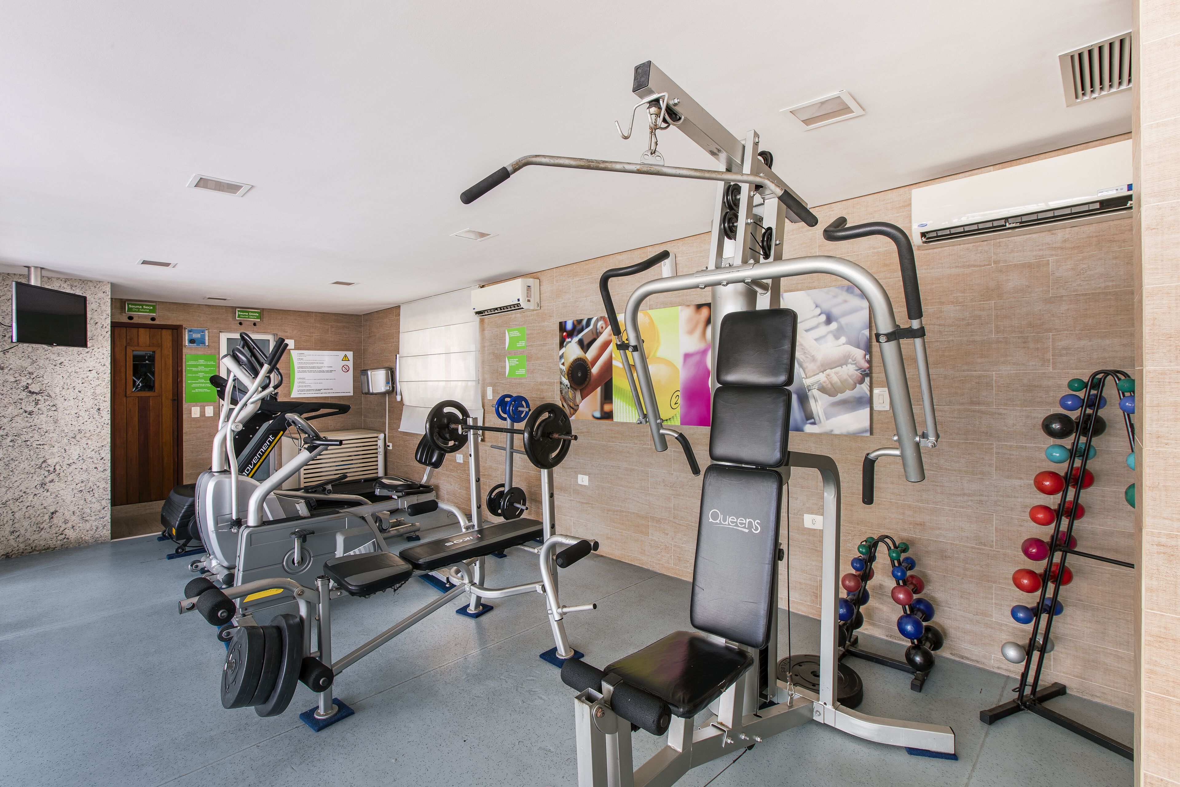 A gym with various exercise equipment, including a treadmill, weight machines, and a pull-up bar.