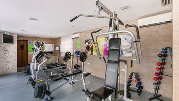 A gym with various exercise equipment, including a treadmill, weight machines, and a pull-up bar.