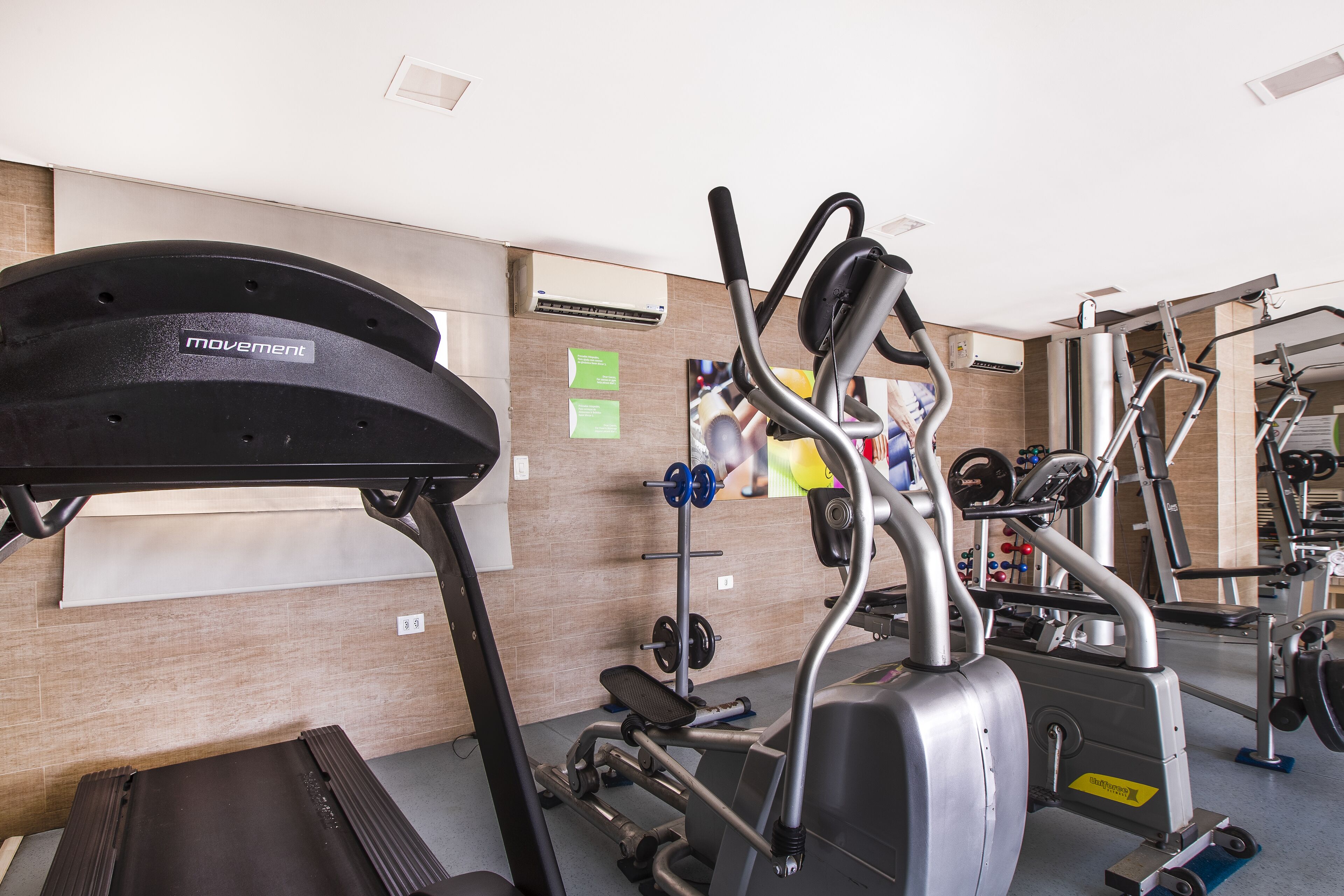 A gym with exercise equipment, including a treadmill, elliptical, and weight machines.