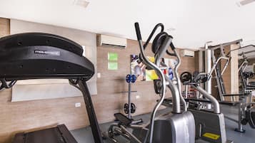 A gym with exercise equipment, including a treadmill, elliptical, and weight machines.