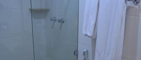 A bathroom with a glass-enclosed shower, a toilet, and a sink with a towel rack.