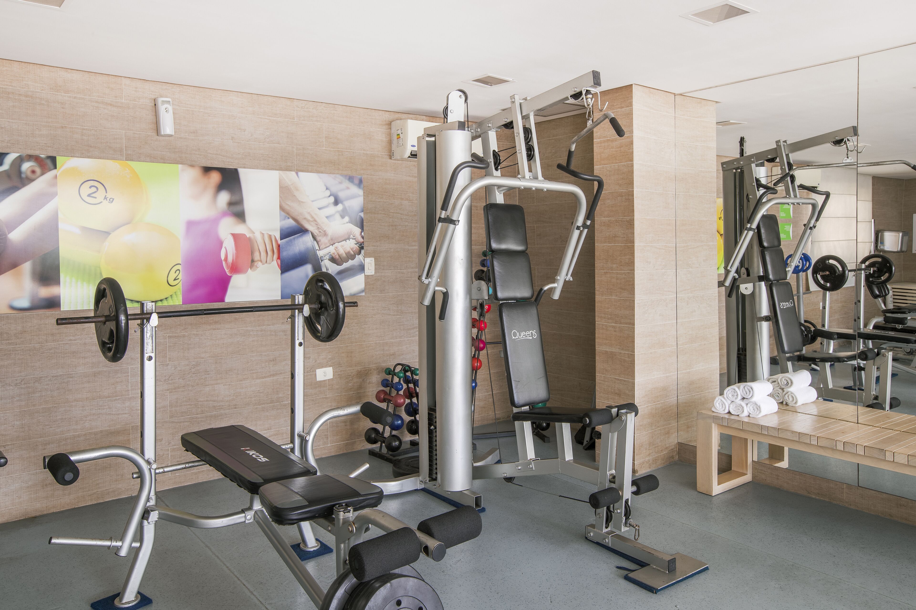 A gym with weightlifting equipment, a bench, and a mirror.