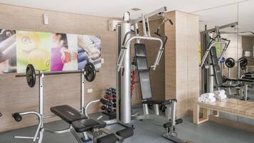 A gym with weightlifting equipment, a bench, and a mirror.