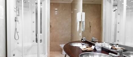 Un baño moderno con ducha envuelta en vidrio, tocador con lavabo y espejo.