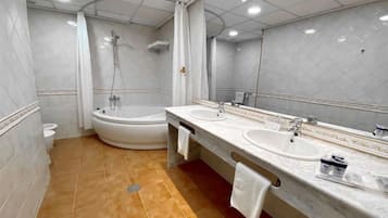 Un baño moderno con una bañera grande, dos lavamanos y una ducha.