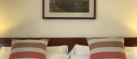A bed with striped pillows and a framed painting above it.