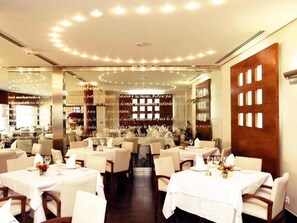 Un restaurante con mesas redondas, manteles blancos y sillas.