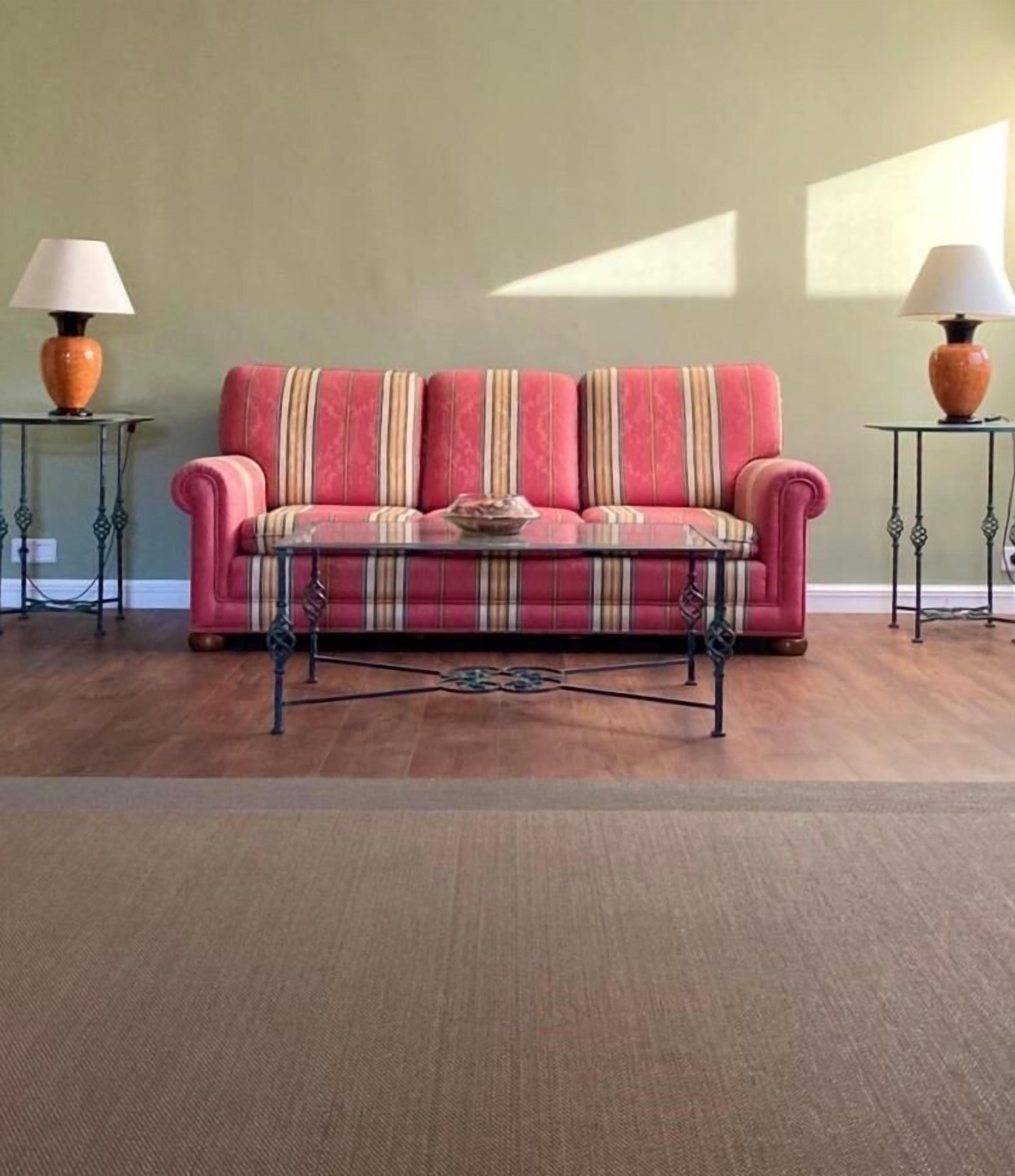A living room with a red sofa, a glass coffee table, and two side tables with lamps.
