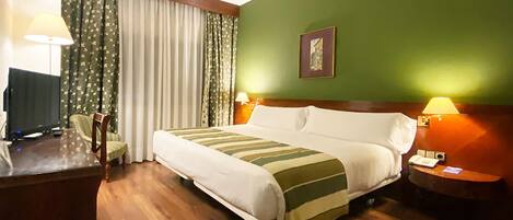 Una habitación de hotel con una cama, dos mesitas de noche con lámparas, un escritorio con televisor y una silla.