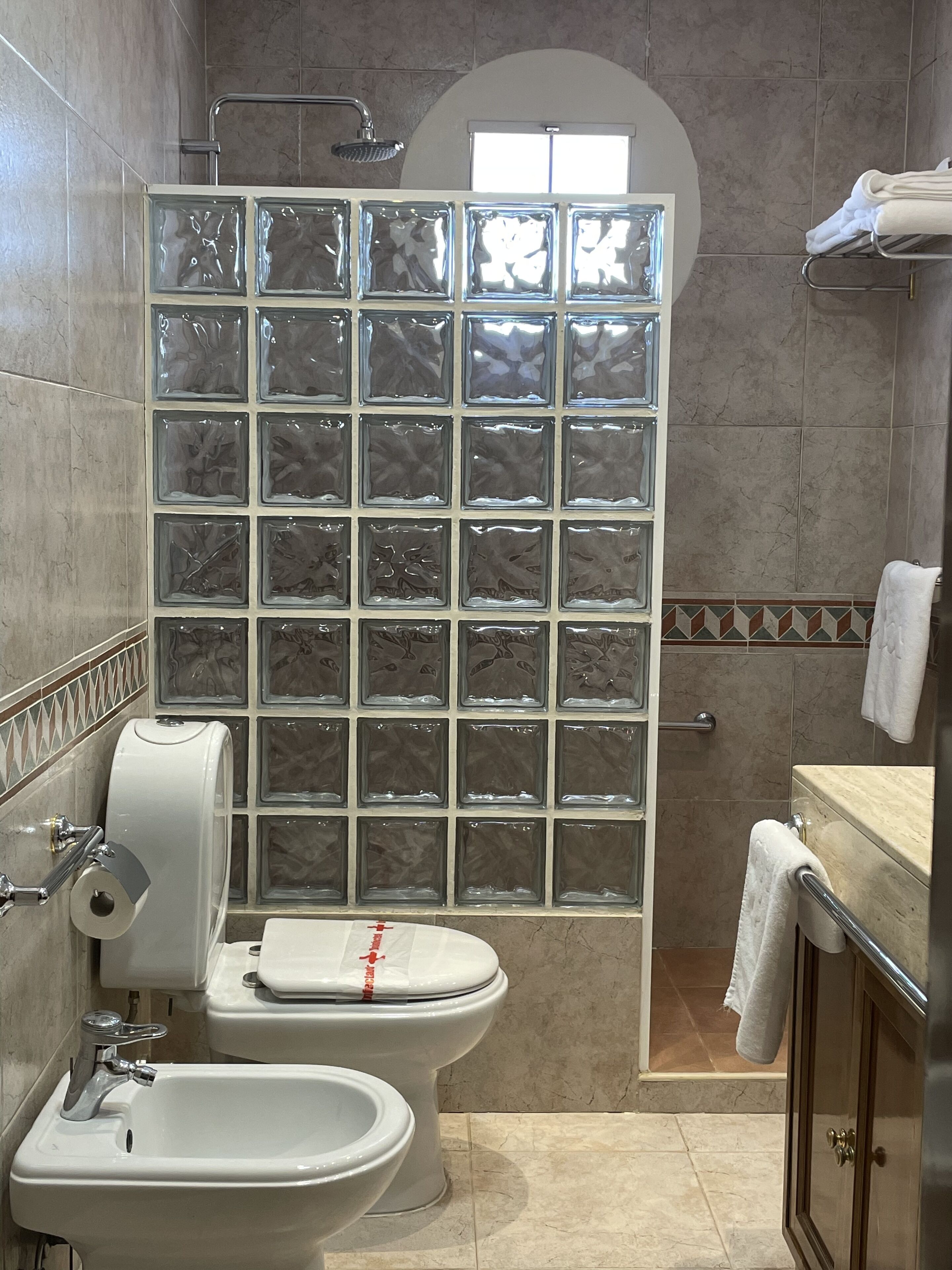 Un baño con cabina de ducha de vidrio, inodoro, bidé y lavamanos.