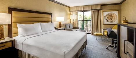 Une chambre d’hôtel avec un grand lit, un bureau, une chaise, une télévision et un balcon avec des rideaux.