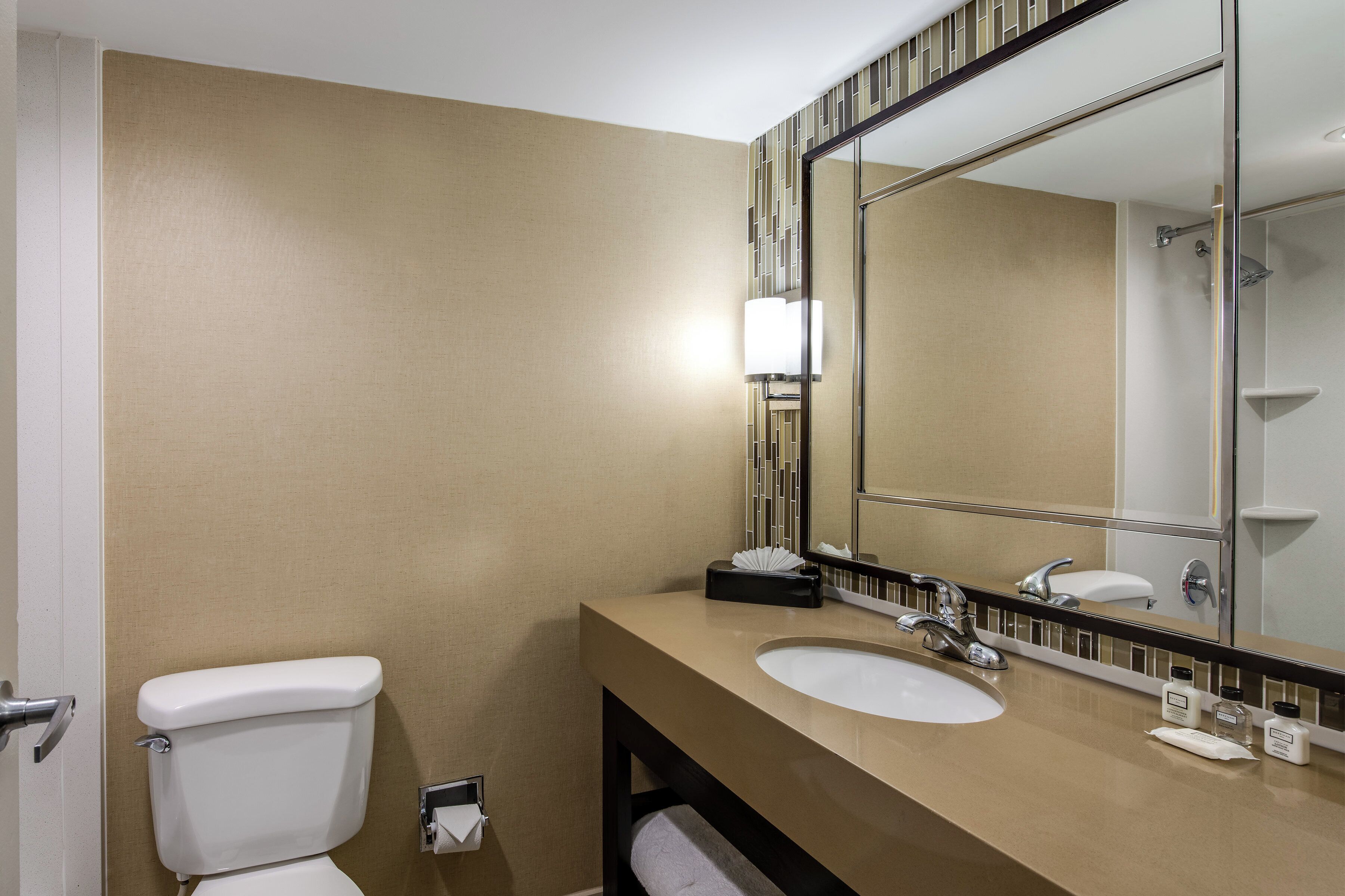 A bathroom with a toilet, sink, and mirror.