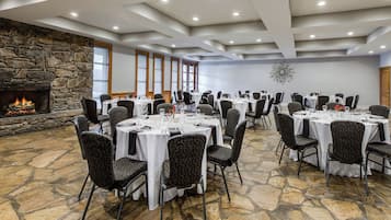 A conference room with round tables, chairs, a stone fireplace, and a decorative wall piece.