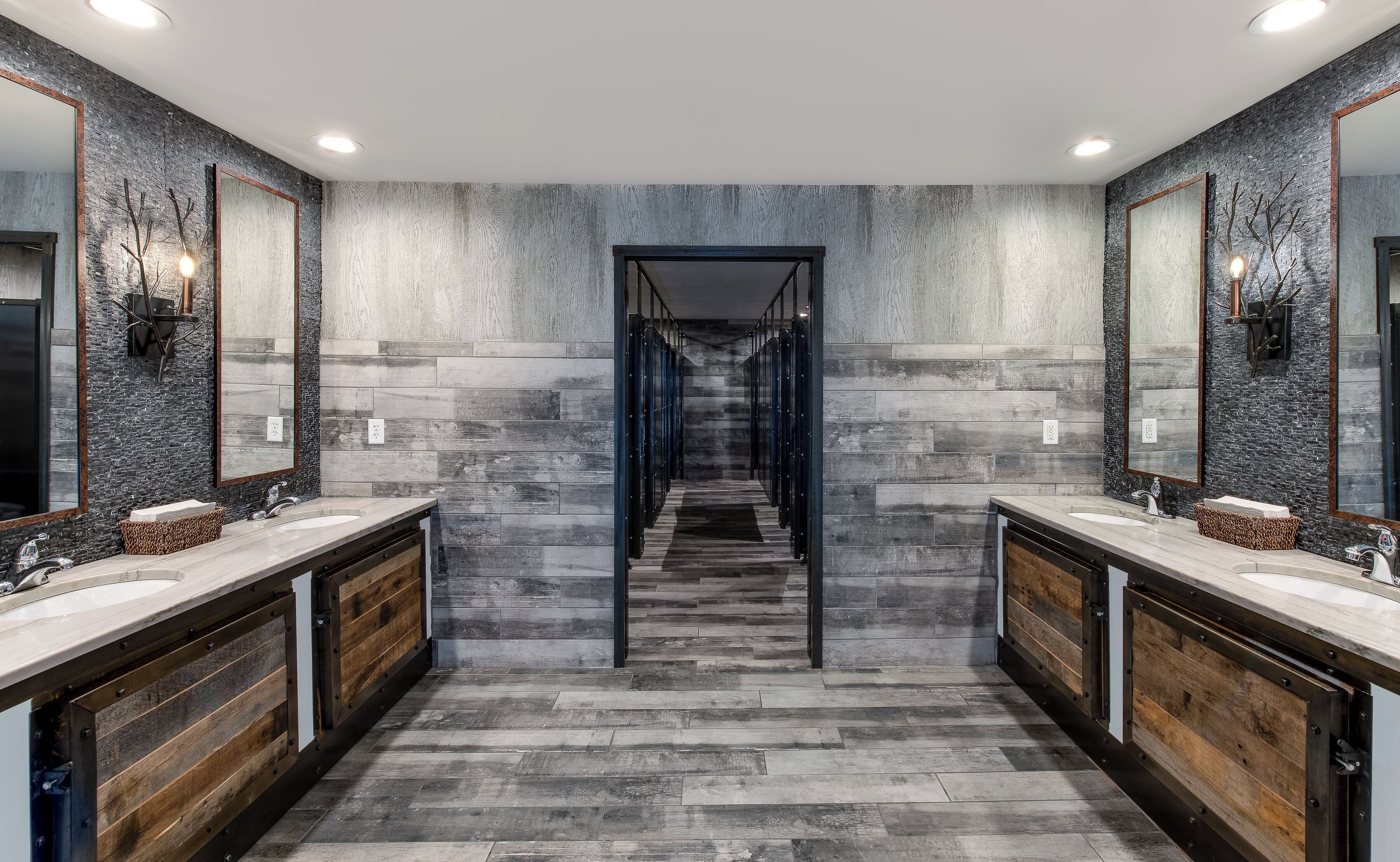Une salle de bain moderne avec deux lavabos, un escalier central et un mur à texture.
