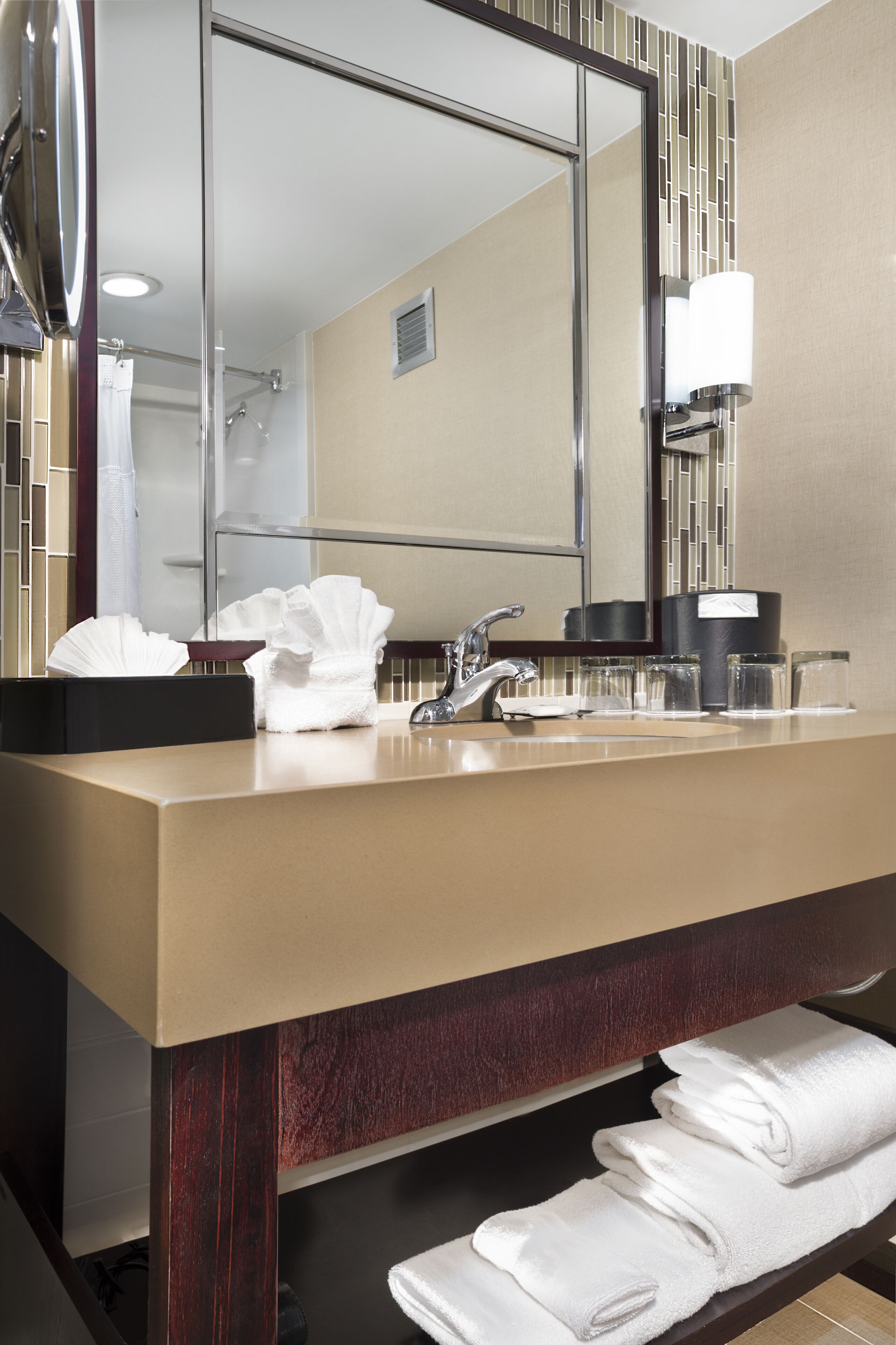 A modern bathroom with a large mirror, a sink, and a towel rack.