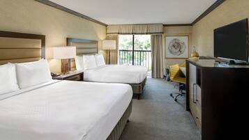 A hotel room with two beds, a desk, a chair, a television, and a window with curtains.