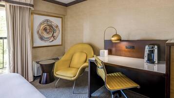 Une chambre d’hôtel avec un lit, un bureau doté d’une machine à café, une chaise et un tableau accroché au mur.