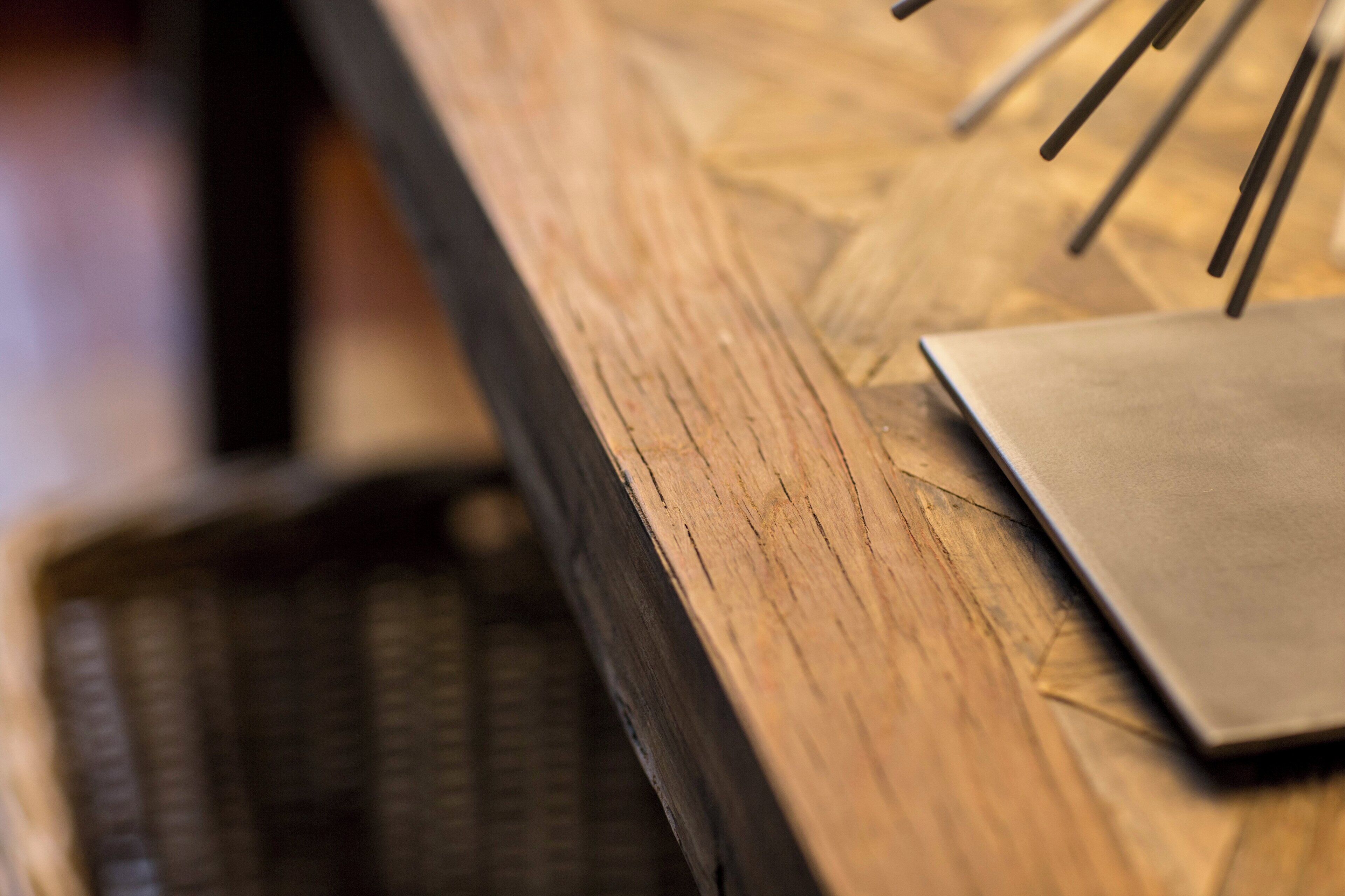 A close-up of a wooden surface with a metal object on it.